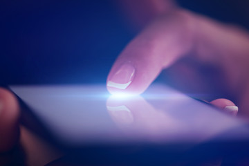 Finger touching phone with dark background with copyspace
