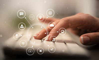 Business woman hand typing on keyboard with application icons around
