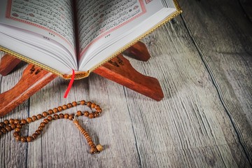 Islamic Concept: The Holy Qoran against wooden background.