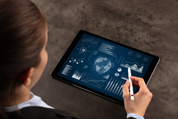 Business woman verifying reports on tablet with pencil in business suit
