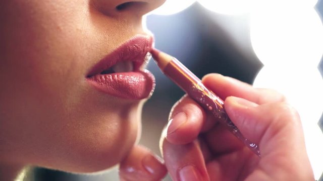 cropped view of makeup artist applying beige lip pencil on model lips