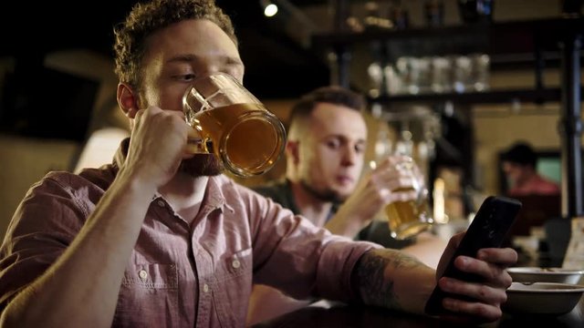 Man with a mobile phone drinking draft beer in a pub