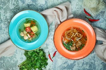 Multi-colored plates with different soups. Gray light textured background. Beautiful serving dishes. Restaurant menu