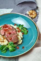 White rice with beef. Rizzotto. Gray light textured background. Beautiful serving of dishes