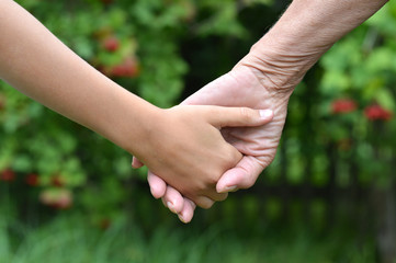 Two people holding hands at the nature close up