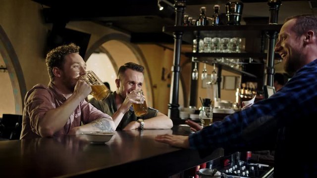 Cheerful friends drinking draft beer in a pub