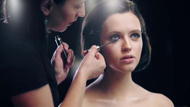 cropped view of makeup artist applying mascara on model eyelashes with cosmetic brush