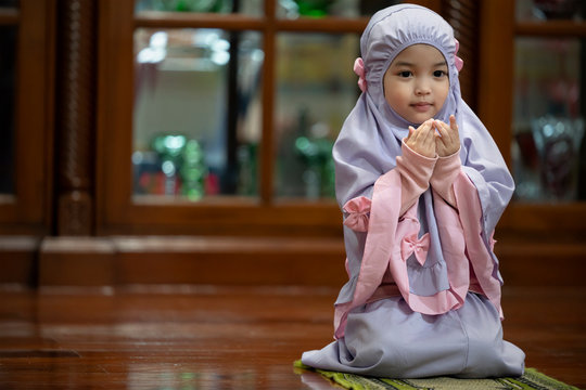 Muslim kid girl wearing Hijab praying Dua during Ramadan period. The concept is Islam,Dua,religion,worship and sin.
