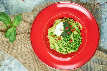 Spaghetti with fresh green peas. Gray textured background with beige fabric. Beautiful serving of dishes. Restaurant menu