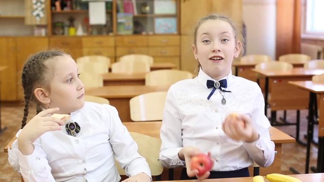 School lunch for children on the break between classes. Schoolgirl girls dine at school with apples fruit and sandwiches with cheese and sausage.