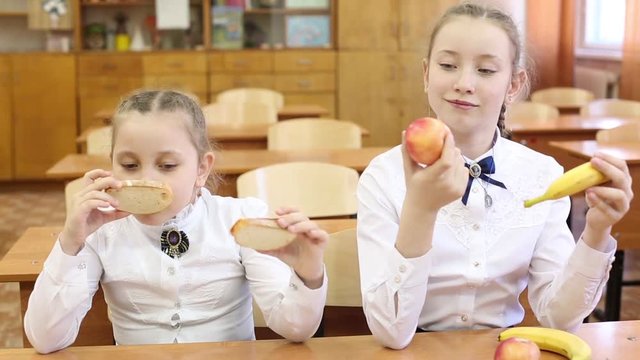 School lunch for children on the break between classes Schoolgirl girls dine at school with apples, fruit and sandwiches with cheese and sausage.