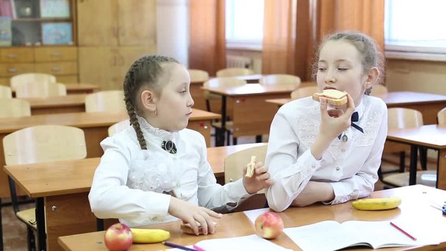 School lunch for children on the break between classes. Schoolgirl girls dine at school with apples, fruit and sandwiches with cheese and sausage.