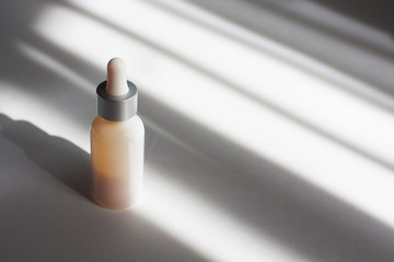White serum bottle on grey shadowed background. Concept beauty composition, concept skin treatment