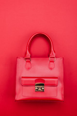 Bright summer fashion ladies accessories. Stylish red leather handbag or flap bag on a red background. Top View. Flat Lay. Copy Space.