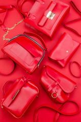Set of different types of red fashion women handbags on red background. Fashion poster concept. Pile of fashion women background. Top View. Flat Lay. Mock up. Card design.