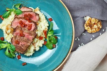 White rice with beef. Rizzotto. Gray light textured background. Beautiful serving of dishes