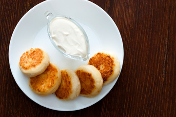 Fried cheese pancakes with sour cream , with space for text on the right. For cafe or restaurant menu design.