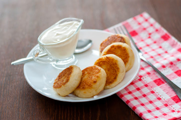 Fried cheese pancakes with sour cream on a white plate view from the top. Can be used for menu design.