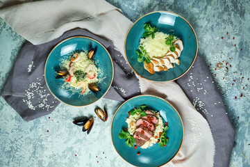 Blue plates with risotti. Gray light textured background. Beautiful serving dishes. Restaurant menu