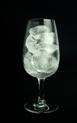 Ice cube in wine glass on black background