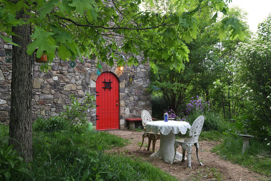 "Al Fresco Dining" unretouched stone cottage with arched mahogany door and table set for outdoor dining in the blue ridge mountain forest ZDS Rural Life Gallery