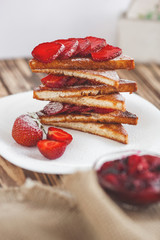 Morning breakfast. Toasts with strawberry and jam. Bread and confiture. Fresh hot toasts with cream. Delicious homemade dessert.