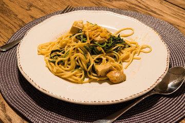 Homemade Spaghetti with Baby Spinach and Chicken at Dinner Table with Glass of Wine.