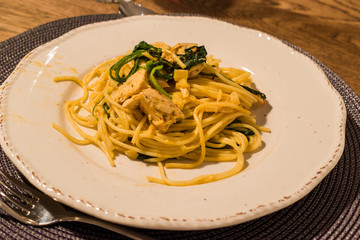 Homemade Spaghetti with Baby Spinach and Chicken at Dinner Table with Glass of Wine.