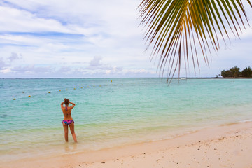 Fototapeta na wymiar woman standing on a beach with coconut tree