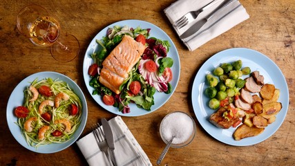Salmon salad, shrimp and pork meat on rustic wooden table from above