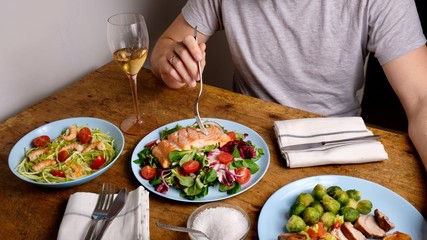 Man sitting with wine and tasty diner, salmon salad shrimp and pork meat