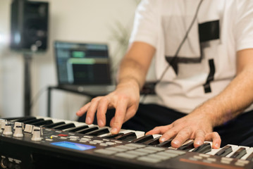 Fototapeta premium Close up of musician playing midi keyboard in home music studio.