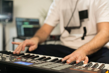 Fototapeta premium Close up of musician playing midi keyboard in home music studio.