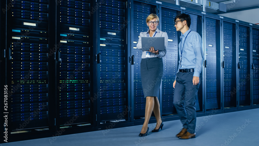 Aufkleber In the Modern Data Center: Engineer and IT Specialist Work with Server Racks, Talking, Doing System Maintenance Check with Laptop Computer. Specialists Doing Diagnostics of the Database.