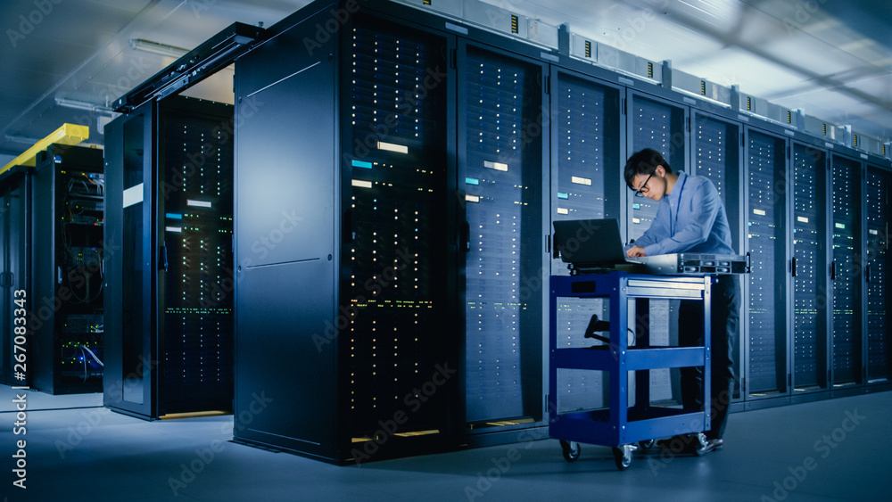Poster In the Modern Data Center: IT Engineer Doing Maintenance and Diagnostics. Pushes Cart alongside Server Racks, Ready to Install New Hardware for Planned System Update, Equipment Replacement.