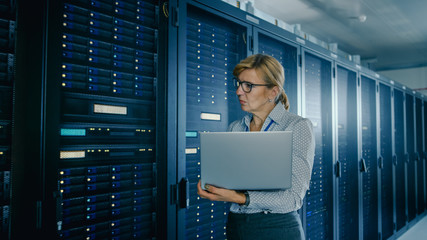 In Data Center: Female IT Technician Running Maintenance Programme on a Laptop, Controls...