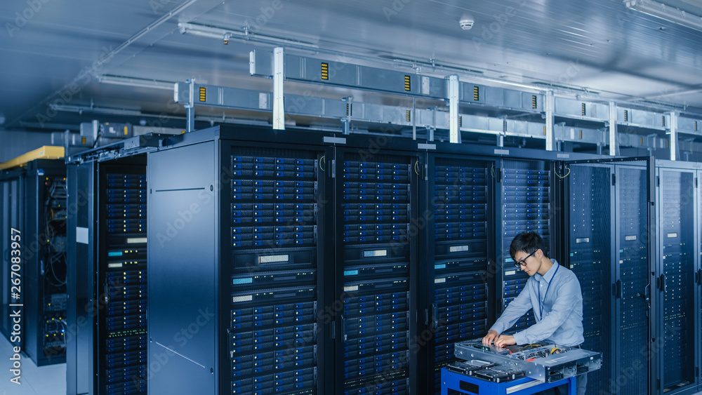 Poster In the Modern Data Center: IT Technician Working with Server Racks, on a Pushcart Various Equipment Needed for Installing New Hard Drives, Doing Hardware Maintenance and Diagnostics.