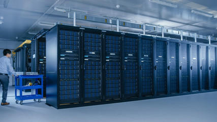 In the Modern Data Center: Team of IT Technicians Working with Server Racks, Running Maintenance and Diagnostics, Checking Networking and Cloud Computing Optimal Functioning.