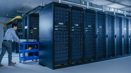 In the Modern Data Center: Team of IT Technicians Working with Server Racks, Running Maintenance and Diagnostics, Checking Networking and Cloud Computing Optimal Functioning.