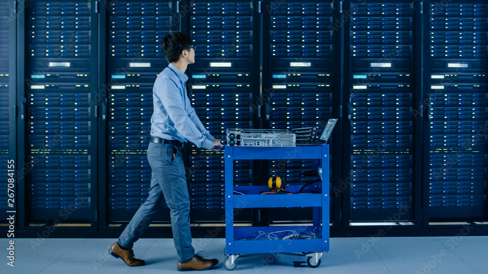 Poster In the Modern Data Center: IT Engineer Pushes Cart alongside Server Racks and Cabinets to Install New Hardware for Planned System Update, Equipment Replacement.