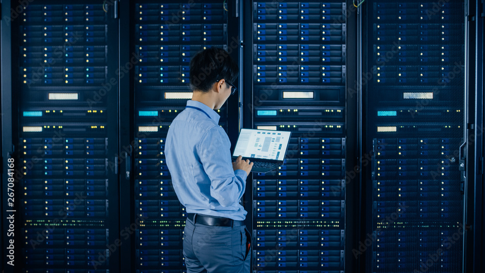 Aufkleber In the Modern Data Center: IT Engineer Standing Beside Open Server Rack Cabinets, Does Wireless Maintenance and Diagnostics Procedure with a Laptop.