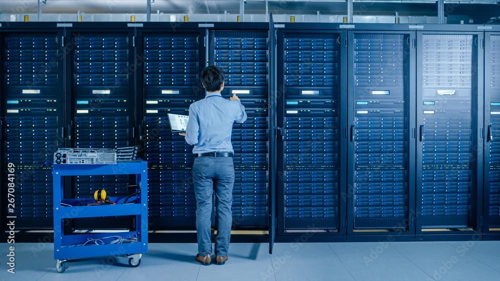 Aufkleber In the Modern Data Center: IT Engineer Doing Maintenance and Diagnostics. Works with Opened Cabinet and Installs New Hardware for Planned System Update, Replacement. Cart Stand alongside Server Racks.