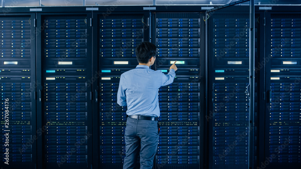 Fototapete in the modern data center: it engineer standing beside open server rack cabinets, does wireless main