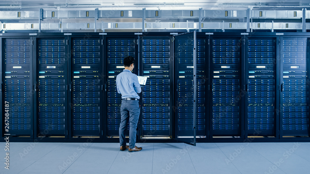 Aufkleber In the Modern Data Center: IT Engineer Standing Beside Open Server Rack Cabinets, Does Wireless Maintenance and Diagnostics Procedure with a Laptop.