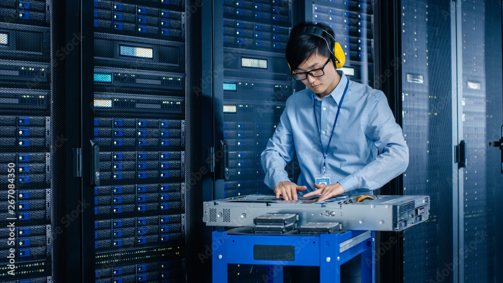 Aufkleber In the Modern Data Center: IT Engineer Wearing Protective Muffs Installs New Hardware for Server Rack. IT Specialist Doing Maintenance, Updating Hardware for Stable Functioning of Database System.