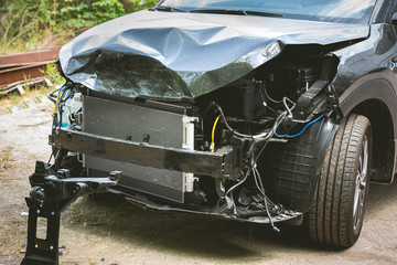 Broken and crashed modern black car after an accident on street, damaged automobile after collision...