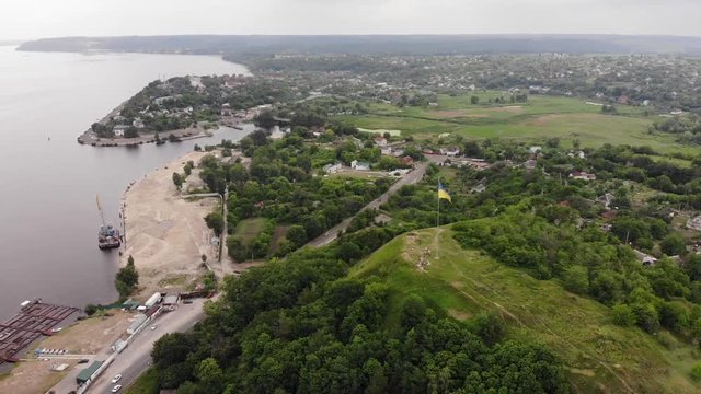 Aerial view. Ukrainian flag on the hill near big water reservoir.