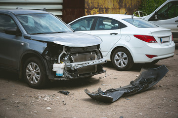 Broken and crashed modern cars after an accident on street, damaged automobile after collision at...