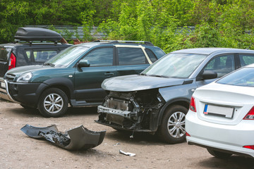 Broken and crashed modern cars after an accident on street, damaged automobile after collision at...