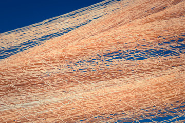 Nylon fishnet texture on the clear sky. Nautical marine background. Macro closeup.
